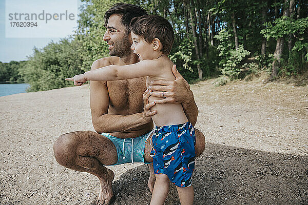 Glücklicher Vater und Sohn zeigen am Wochenende auf das Seeufer
