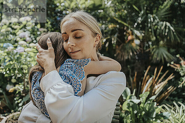 Mutter umarmt Tochter im Hinterhof