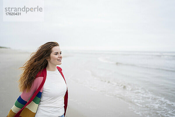 Lächelnde rothaarige Frau genießt das Wochenende am Strand