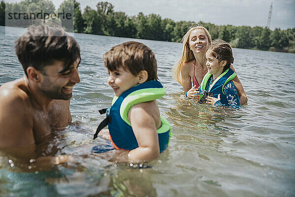 Glückliche Eltern  die mit Kindern im See spielen