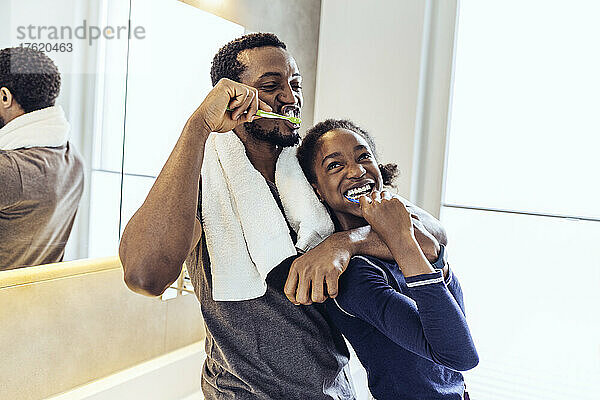 Vater und Tochter putzen zu Hause im Badezimmer die Zähne