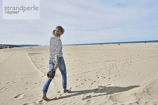 Frau geht am Strand auf Sand