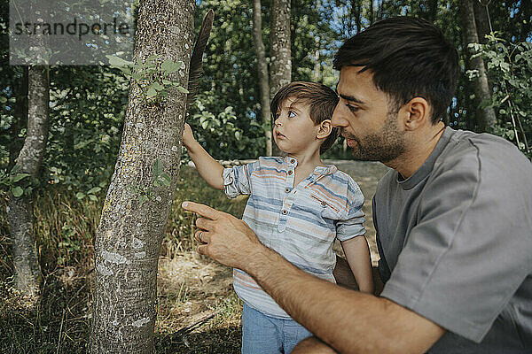 Father and son looking at tree in nature