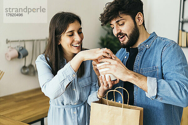Lächelnde Frau und Mann halten eine Kiste in der Küche zu Hause