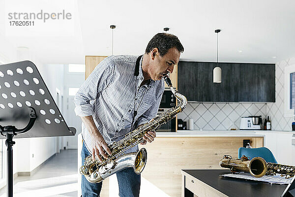 Musiker spielt Saxophon in der Küche am heimischen Tisch