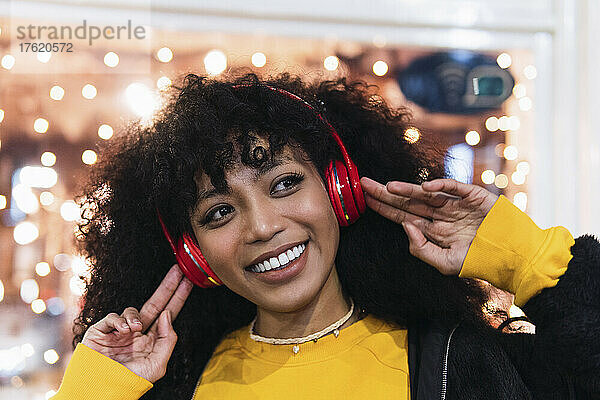 Schöne glückliche Frau  die nachts Musik über kabellose Kopfhörer genießt