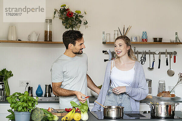 Lächelnder junger Mann und Frau unterhalten sich zu Hause in der Küche