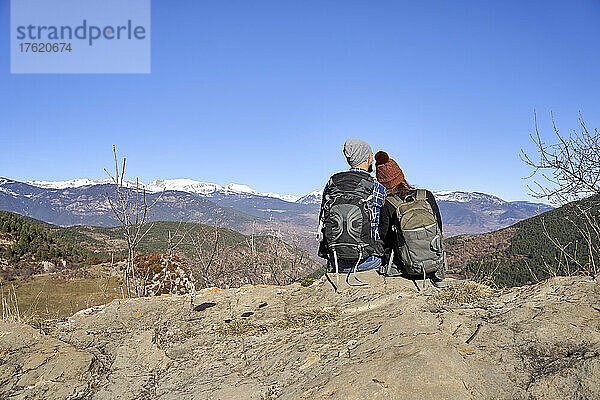 Paar sitzt zusammen auf einem Felsen und genießt die Aussicht