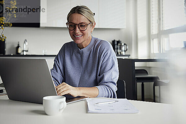 Happy businesswoman using laptop at table