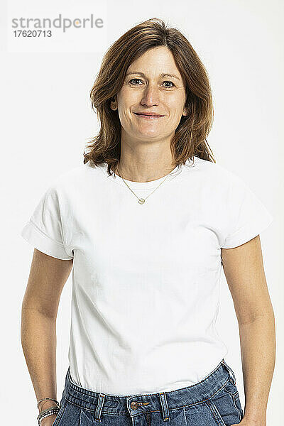 Smiling woman standing with hands in pocket against white background