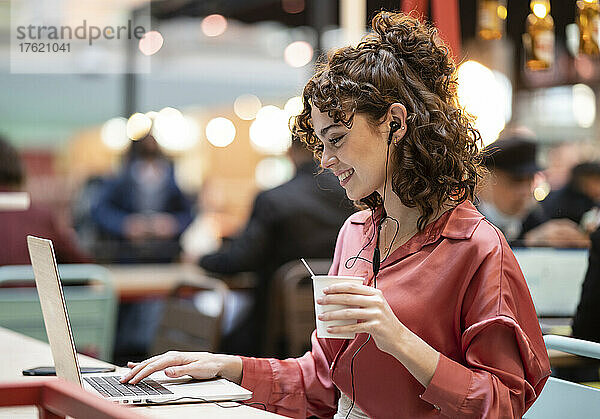 Junge Geschäftsfrau tippt im Café am Laptop
