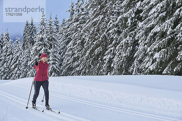 Ältere Frau fährt im Winterwald Ski