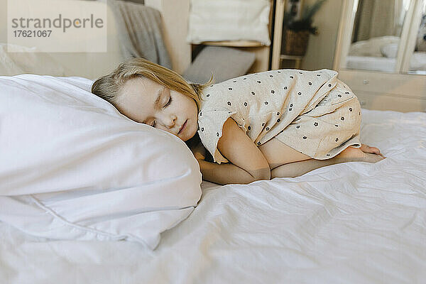 Blondes Mädchen schläft zu Hause im Bett