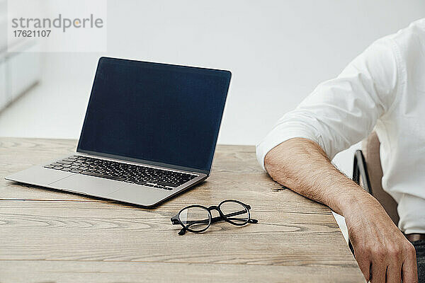 Geschäftsmann mit Laptop auf Schreibtisch im Startup-Büro