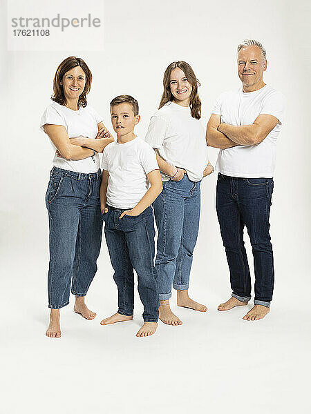 Children standing with hands in pocket with parents arms crossed at studio