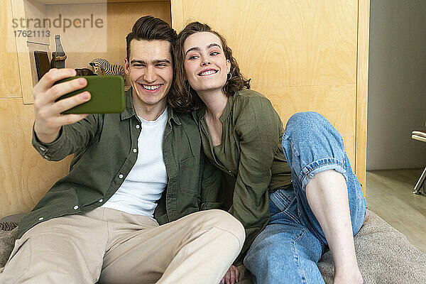 Glückliches junges Paar  das zu Hause ein Selfie mit dem Handy macht