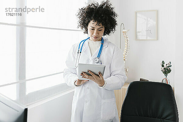 Arzt benutzt Tablet-PC  der am Fenster einer medizinischen Klinik steht