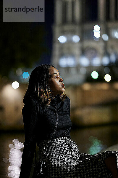 Nachdenkliche Frau sitzt nachts auf dem Fußweg