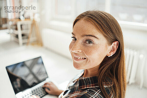 Lächelnde Frau mit Laptop zu Hause
