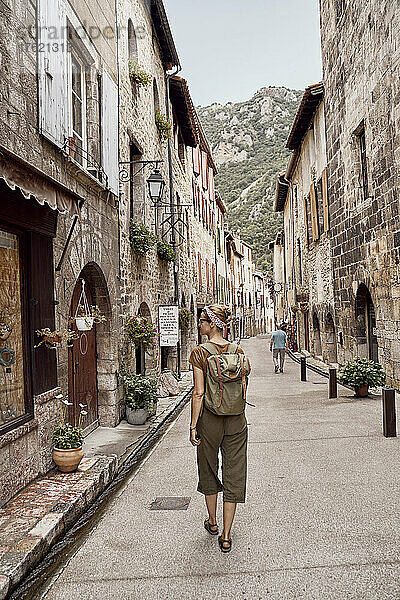 Frau mit Rucksack spaziert durch die Stadt Villefranche-de-Conflent