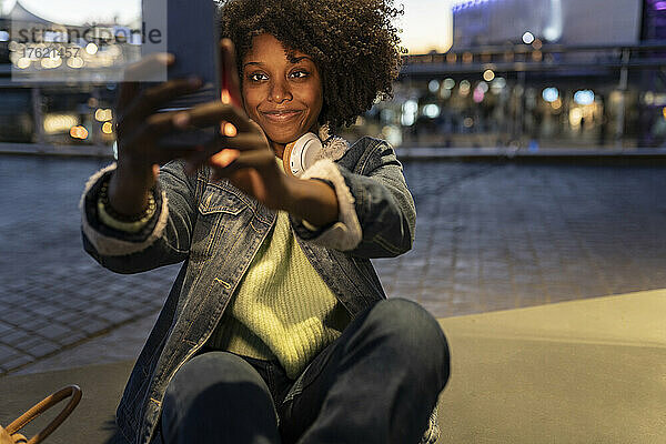 Lächelnde junge Frau  die nachts ein Selfie mit dem Smartphone macht