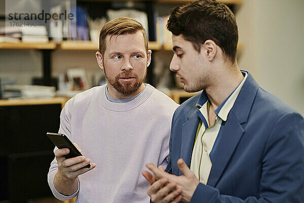 Geschäftsleute diskutieren im Büro über das Smartphone miteinander