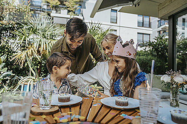 Glückliche Eltern unterhalten sich mit Kindern auf einer Geburtstagsfeier im Hinterhof