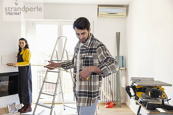 Young couple measuring room at home renovation work