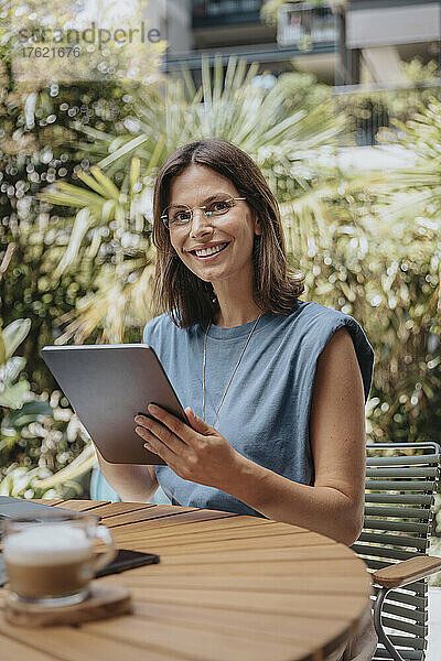 Lächelnde Geschäftsfrau mit Tablet-Computer im Hinterhof