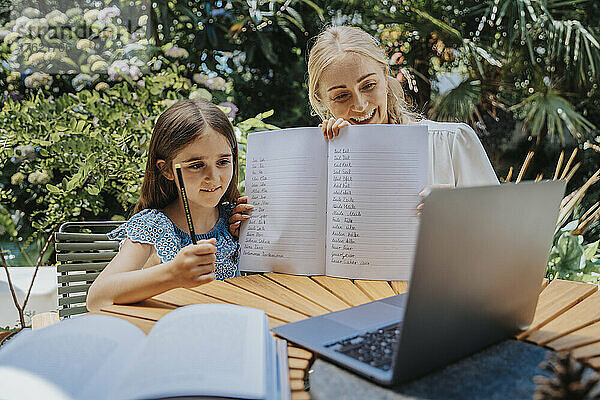 Tochter und Mutter zeigen Hausaufgaben per Videoanruf über Laptop