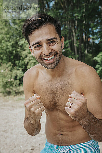 Smiling shirtless man at lakeshore