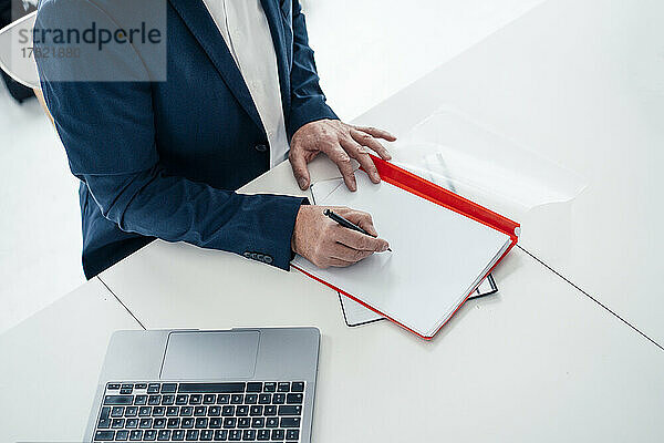 Geschäftsmann schreibt im Büro mit Stift auf Akte