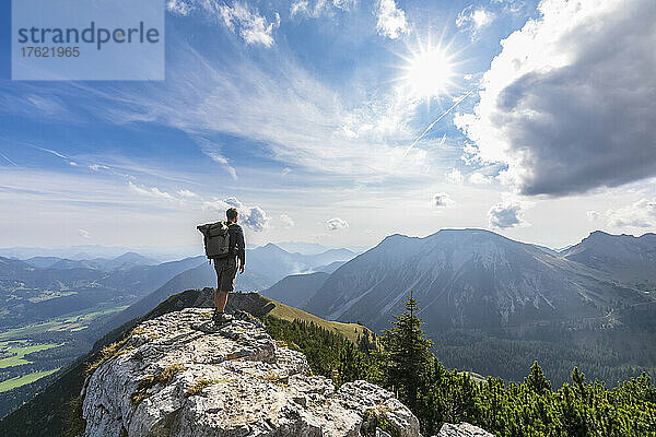 Männlicher Wanderer  der die Aussicht vom Gipfel des Aiplspitz-Berges bewundert