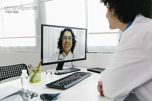 Arzt führt Videoanruf mit Kollegen über Desktop-PC in der Klinik
