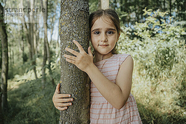 Innocent girl embracing tree in nature