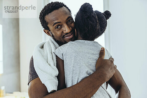 Lächelnder Vater umarmt Tochter zu Hause