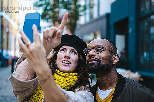 Frau zeigt und macht Selfie mit Mann auf Smartphone