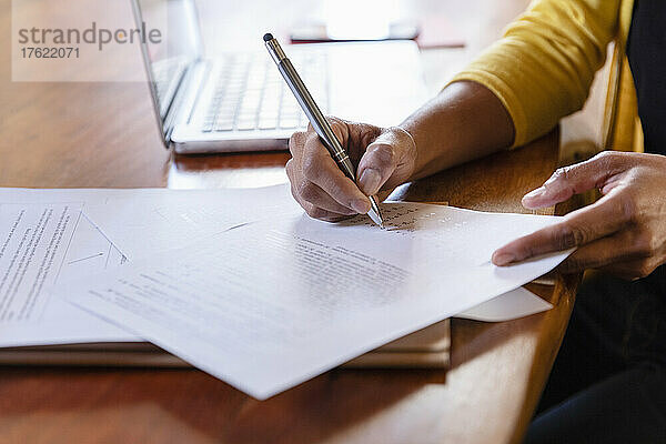 Freiberufler unterzeichnet Papierdokument auf dem Schreibtisch zu Hause