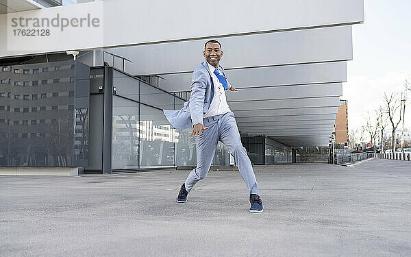 Lächelnder Geschäftsmann tanzt vor dem Gebäude
