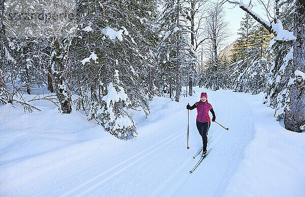 Ältere Frau mit Skistock fährt im Urlaub im Schnee Ski