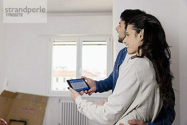 Junges Paar hält Tablet-PC im neuen Zuhause