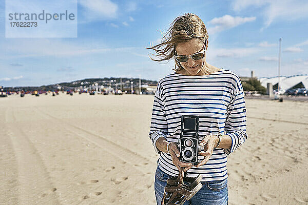Tourist mit Vintage-Kamera steht an sonnigem Tag am Strand