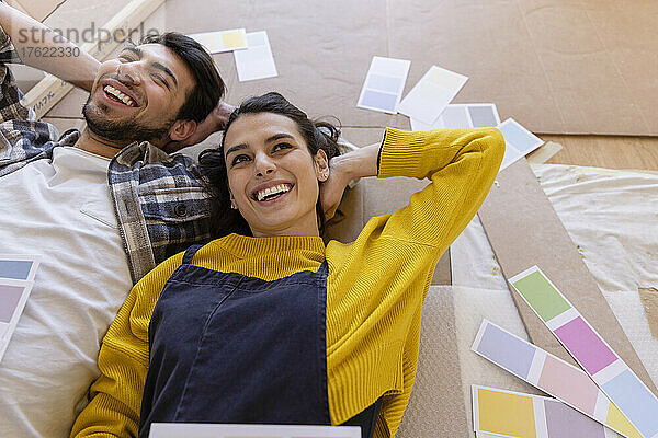 Lächelndes Paar träumt Tag mit Farbmustern im neuen Wohnzimmer