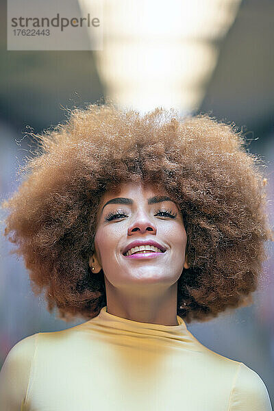 Lächelnde schöne Frau mit rothaariger Afro-Frisur