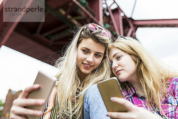 Lächelnder Teenager macht Selfie mit Freund per Handy
