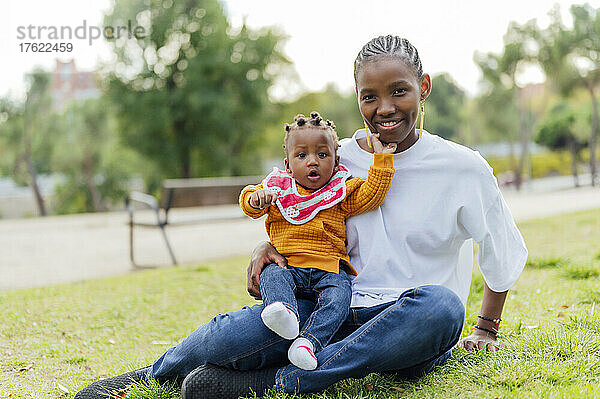 Lächelnde Mutter mit süßer Tochter  die im Park sitzt
