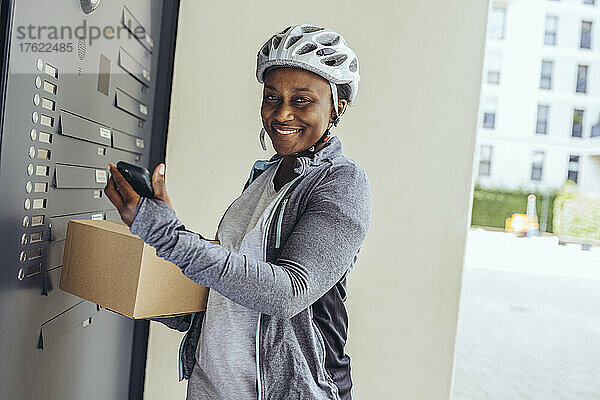 Lächelnde Lieferfrau mit Paketkarton an der Eingangstür