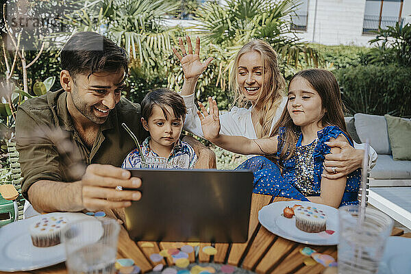 Familie winkt per Videoanruf über Tablet-PC im Hinterhof