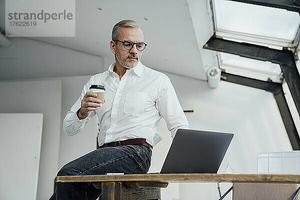 Architekt sitzt mit Laptop am Schreibtisch im Büro