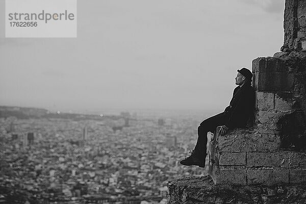 Nachdenklicher Mann sitzt auf einem Felsen in der Stadt